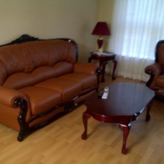 A cozy living room with a leather sofa set, coffee table, and lamp.