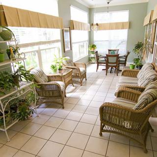 A bright sunroom with wicker furniture and lush indoor plants.