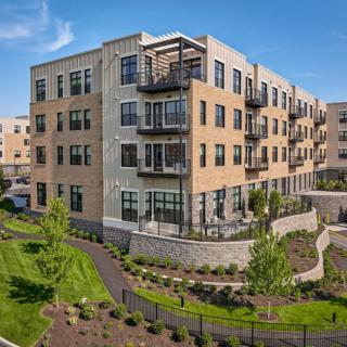 A modern residential apartment building with balconies and landscaped surroundings.