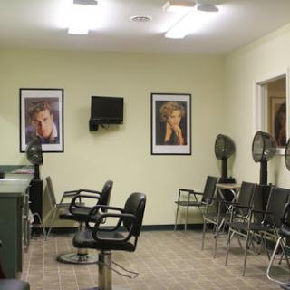 A cozy hair salon featuring styling chairs, a waiting area, and framed posters on the walls.