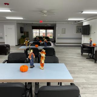 A community room decorated with autumn-themed items and pumpkins on tables.