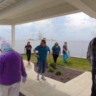 A group of people walking under a shelter by the lake on a cloudy day.