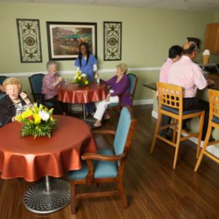 Elderly residents socializing in a care facility with staff assistance.