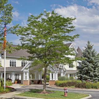 A residential building with a tree in the foreground and a partly cloudy sky.