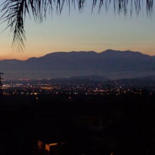 A cityscape view at dusk with mountains silhouetted against the sunset.