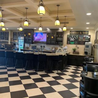 A cozy cafe interior with a checkered floor, bar counter, and hanging lights.