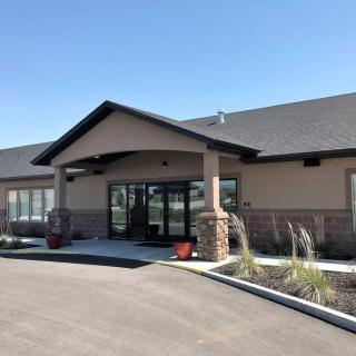 A modern commercial building with a landscaped entrance and clear blue sky.