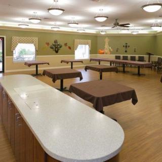 A spacious room with multiple tables and a countertop, decorated with warm lighting.