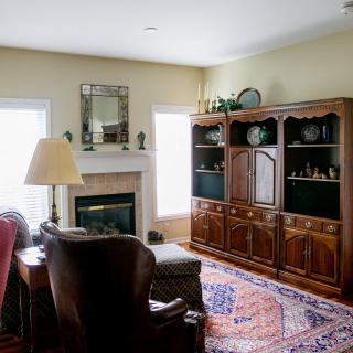 A cozy living room with a fireplace, armchair, and bookshelf.
