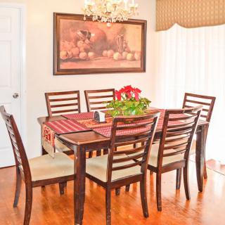 A cozy dining room with a wooden table and chairs, adorned with a chandelier and wall art.