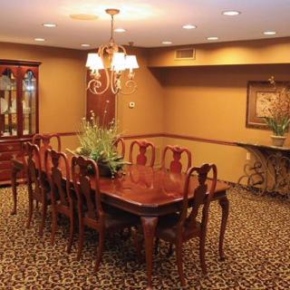 A traditional dining room with a wooden table and chairs, illuminated by a chandelier.