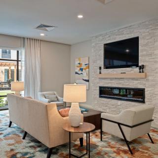 A modern living room with stylish furniture, featuring a stone wall with a mounted television and fireplace.
