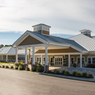 A modern building with a prominent entrance and landscaped surroundings under a clear sky.