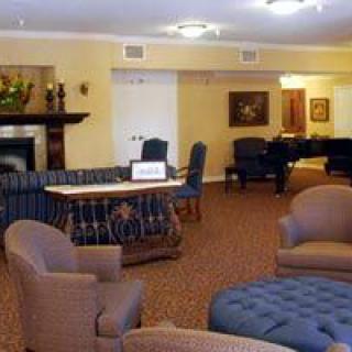 A cozy living room with comfortable seating, a piano, and a fireplace.