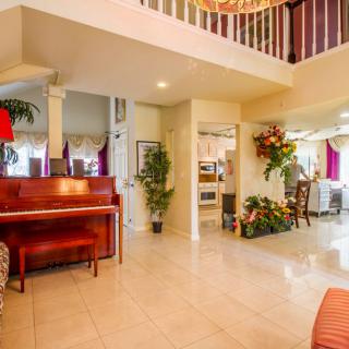 A spacious and bright living area featuring a piano, plants, and elegant interior design elements.