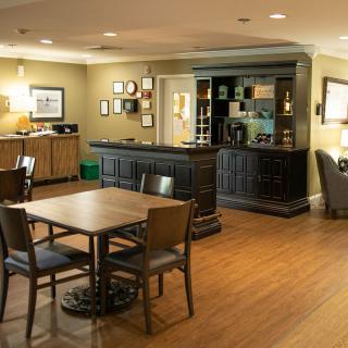 A cozy living room setup with a wooden table and chairs, a cabinet, and soft lighting.