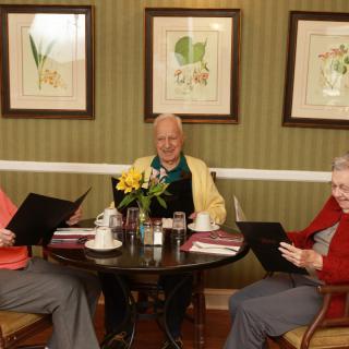 Three elderly friends enjoy a meal together at a restaurant.