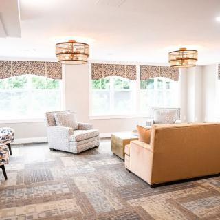 A bright and spacious living room featuring comfortable seating, large windows, and elegant lighting fixtures.