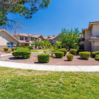 A well-maintained suburban housing complex with landscaped gardens and a clear blue sky.