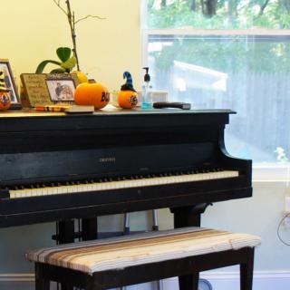 A room with a piano decorated with pumpkins and photos.
