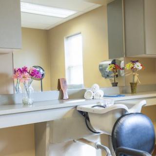 A clean and well-decorated dentist office with a dental chair and flowers.