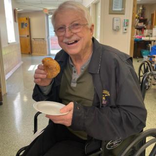 A joyful senior man enjoying a snack in a wheelchair.