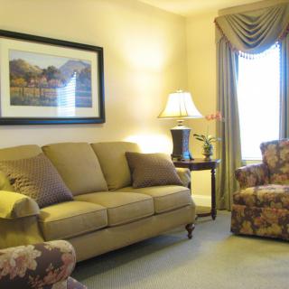 A cozy living room with a sofa, lamp, and artwork on the wall.