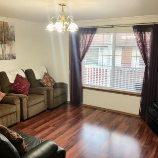 A cozy living room with hardwood floors, comfortable sofas, and a large window with curtains.