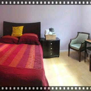 A cozy bedroom with a colorful bedspread, nightstand, and a comfortable chair.