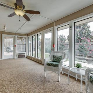 A bright sunroom with large windows, comfortable seating, and a ceiling fan.