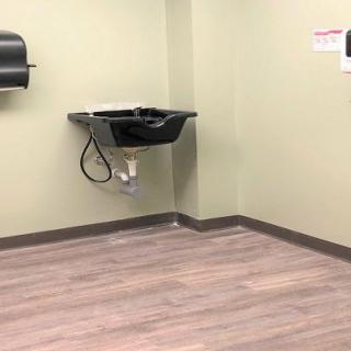 A bathroom corner with a black sink and soap dispenser on a beige wall.