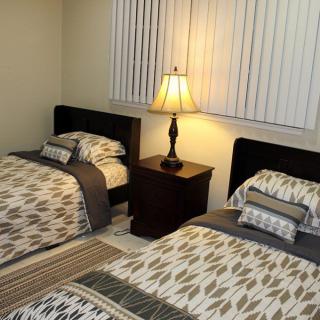 A cozy bedroom with two neatly made twin beds and a warm lamp on the nightstand.