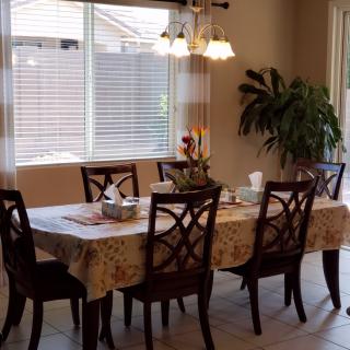 A cozy dining room with a table set for a meal, featuring elegant chairs, a tablecloth, and ambient lighting.