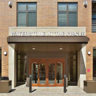 Entrance of a building with glass doors and windows, labeled 'WATERSTONE AT THE CIRCLE'.