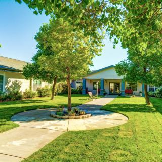 Sunny day in a beautifully landscaped yard with houses and trees.