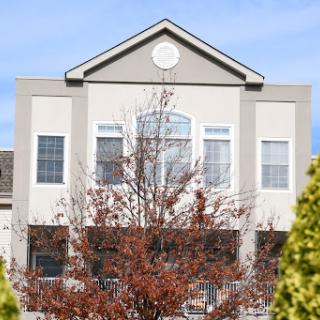 A residential building with large windows framed by a tree in autumn.