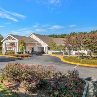 A welcoming entrance to a hospitality establishment surrounded by lush greenery and a clear blue sky.