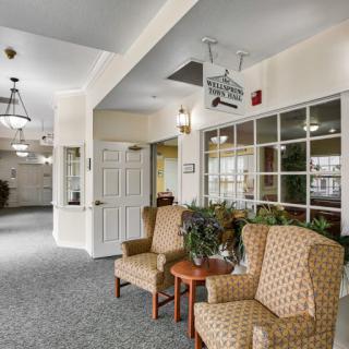 A cozy lobby area with patterned chairs, plants, and large windows.