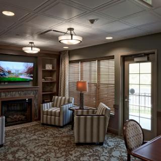 A cozy living room featuring striped armchairs, a television, and a warm fireplace.