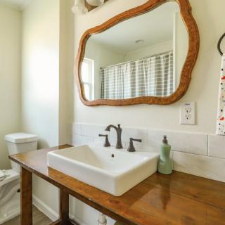 A stylish bathroom with a wooden vanity and unique mirror.