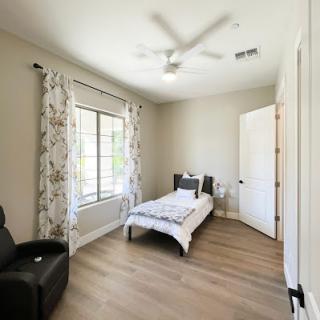 A cozy and modern bedroom featuring a single bed, stylish curtains, and a ceiling fan.