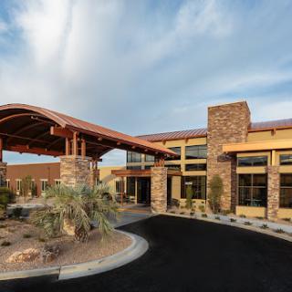 A modern architectural building featuring a stone exterior and desert landscaping.
