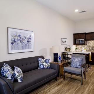 A modern living space with a sofa, chair, and kitchenette.