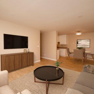 A modern living room with neutral tones, featuring a flat-screen TV, a coffee table, and an adjacent dining area.