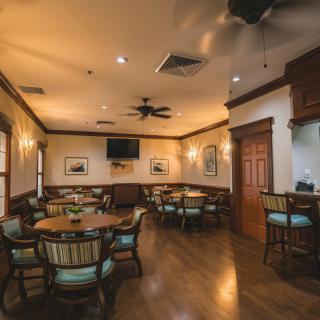 A cozy dining area with wooden floors and elegantly arranged tables and chairs.