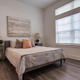 A cozy bedroom with a neatly made bed, decorative pillows, and modern artwork on the wall.