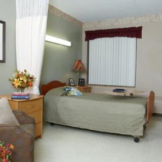 A hospital room with a single bed and cozy furnishings.