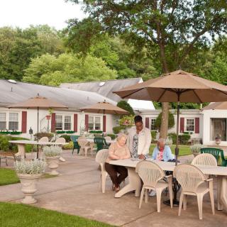 Seniors enjoying a relaxing time on a patio surrounded by trees.