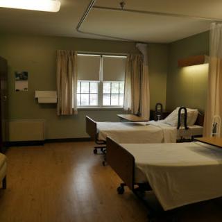 A peaceful hospital room with two patient beds and natural light coming through the windows.