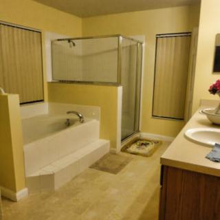 A spacious bathroom featuring a bathtub, shower, and sink with a vanity.